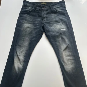 Jack & Jones Slim Glenn jeans  - Snygga svarta jeans från Jack & Jones i modellen Slim Glenn. Jeansen har en slim passform, och slitna detaljer framtill. Storleken är 32/30 och jag säljer dessa för 400
