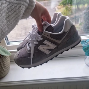 Gråa New Balance 574 - Snygga New Balance 574 Classic sneakers i grå mocka och mesh med vita detaljer och snörning. Ikonisk N-logga på sidan och bekväm platt sula. Inköpt förra året och sparsamt använd. Säljer då jag har andra skor jag använder mer. Storlek 38.5 men passar 38.    Skriv helst meddelande innan köp ☺️