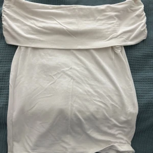 Vit off shoulders från Amisu - Supersnygg vit off shoulders från Amisu i mjukt och stretchigt material. Toppen har en bred, vikt linning som ger en cool och avslappnad look. Perfekt att styla med en jeans kjol eller  kostymbyxor för en fräsch vibe.