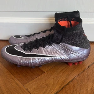 Nike Mercurial fotbollsskor lila/svart - Tja! Säljer ett par feta och sällsynta Nike Mercurial fotbollsskor i metallic lila och svart med orange strumpa (superfly)! Dessa är väldigt unika och oerhört svåra att få tag på, speciellt i detta skick och pris! Kan gå ner lite i pris vid snabb affär! 
