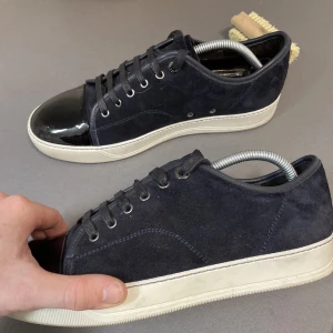 Svarta / Mörkblå sneakers från Lanvin med lacktå - Snygga svarta sneakers från Lanvin med ovandel i mocka och en glansig lackad tå. Skorna har vita gummisulor och svarta skosnören. Perfekt för dig som gillar en stilren men ändå unik look. Kan tänka mig byte om det är skor i bra kvalité och äkta och samma prisklass helst Svart, vit eller grå