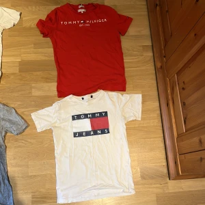Tommy Hilfiger T-shirt - Två snygga t-shirts från Tommy Hilfiger och Tommy Jeans. Den ena är röd med vit logotyptext och den andra är vit. Båda har rund hals och korta ärmar, perfekta för en chill och stilren look. Storelk xs till S. En för 60 eller båda för 100