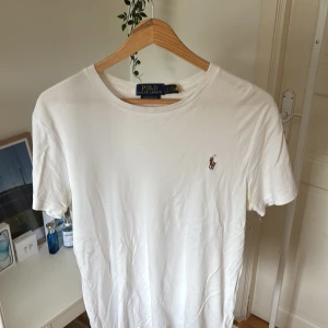 Vit t-shirt från Polo Ralph Lauren - Vit t-shirt från Polo Ralph Lauren med klassisk rund hals och korta ärmar. Slim fit-modell i mjuk bomull. På bröstet finns den ikoniska broderade Polo-loggan med en polospelare. Perfekt basic med stilren design och skön passform. Nypris 1095kr och storlek small.