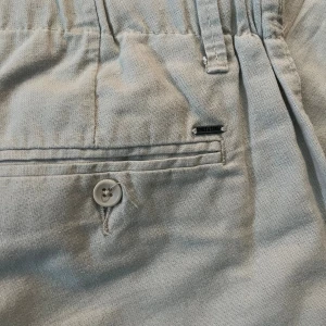 Beige linnebyxor från Only & Sons - Snygga beige linnebyxor från Only & Sons med elastisk midja, knappar och snörning framtill. Byxorna har bakfickor med knapp och bälteshällor. Perfekta för en chill och stilren look under varmare dagar.