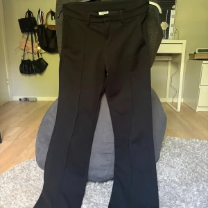 Svarta kostymbyxor  - Snygga svarta kostymbyxor från Kappahl i storlek 164. Byxorna har klassisk rak passform med pressveck och bälteshällor. Materialet är mjukt och har en elegant känsla, perfekt för dig som gillar stilrena och tidlösa plagg. Fickor fram och diskret design. En liten defekter att det är nopprigt under fickan på högraframsidan, men inget som man märker!! Kontakta mig om du har några funderingar!!❤️