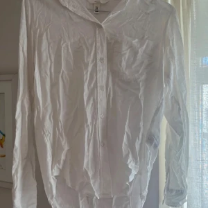 Vit linneskjorta från H&M XS - Snygg vit skjorta från H&M i storlek XS, tillverkad i en skön linneblandning. Klassisk design med krage, bröstficka och knappar framtill. Perfekt för dig som gillar en clean och fräsch stil. Långärmad och lätt material som passar bra till varmare dagar.storlek xs, kan strykas innan post om det önskas. Använd 2 gånger, inga defekter.