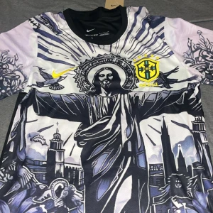 Nike Brasil Dri-Fit ADV fotbollströja S - Unik Brasilien fotbollströja från Nike med Dri-Fit ADV-teknik. Framsidan har ett stort konstnärligt tryck av Kristusstatyn och stadsmotiv i svart, vitt och blått. Bröstet har Brasil-logga och Nike Swoosh i gult. Baksidan är svart med gult namn och nummer.