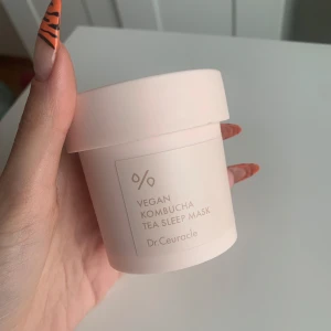 Vegan Kombucha Tea Sleep Mask från Dr.Ceuracle - Vegan Kombucha Tea Sleep Mask från Dr.Ceuracle i en stilren, ljusrosa burk. Masken är krämig och designad för att användas över natten för att återfukta och vårda huden. Perfekt för en nattlig hudvårdsrutin.