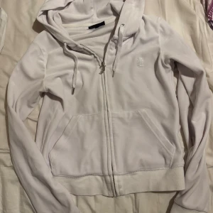 Vit hoodie från Juicy Couture - Säljer en stilren vit hoodie från Juicy Couture. Fint skick men har tappat en metall knapp i ena snöret. 