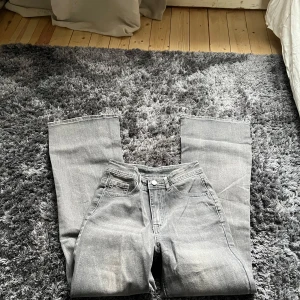 Grå jeans med broderade fickor - Snygga grå jeans med unika broderade detaljer på bakfickorna. Tillverkade i en blandning av bomull, polyester och spandex för en bekväm passform. Perfekta för dig som vill ha något annorlunda i garderoben.