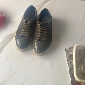 Grå sneakers från Lanvin - Snygga grå sneakers från Lanvin med snörning och en stilren design. Skorna har en mörkare tåhätta och en ljus sula som ger en cool kontrast. Perfekta för en avslappnad stil. Tar gärna emot byten också mot ett par rockrunners saint laurent elr andra lanvin!