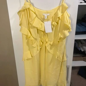Gul klänning från H&M - Säljer en söt gul klänning från H&M med volangdetaljer och smala axelband. Perfekt för soliga dagar och ger en härlig sommarkänsla. 🌼
