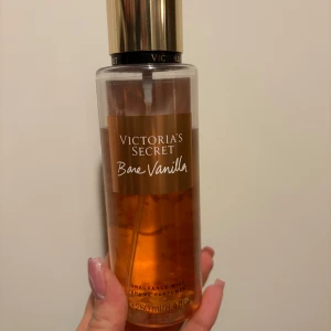 Bare Vanilla Fragrance Mist från Victoria's Secret - Säljer en Bare Vanilla Fragrance Mist från Victoria's Secret. Flaskan är genomskinlig med en gyllene vätska och har en elegant guldlock. Perfekt för dig som älskar en söt och varm vaniljdoft. Flaskan rymmer 250 ml från början, mängden kvar syns på bilden 🥰