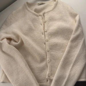 Vit kofta från Gina Tricot - Mysig vit kofta från Gina Tricot i premiumkvalitet. Den har långa ärmar och knappar framtill, perfekt för en stilren look. Passar bra till både jeans och kjol.