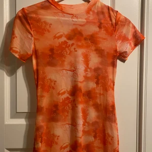 Orange mönstrad klänning! Stretch! S - Säljer en cool orange klänning från Shein med ett unikt mönster. Klänningen har korta ärmar och är tillverkad i polyester och spandex för en bekväm passform. Perfekt för att sticka ut med sin färgstarka design!