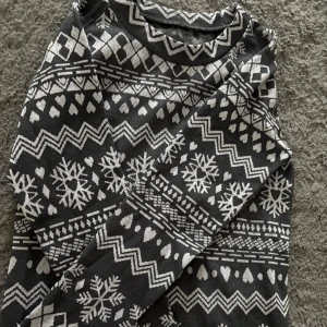 Svart och vit mönstrad tröja - Säljer en svart tröja med vitt mönster av snöflingor och geometriska former. Tröjan har långa ärmar och är perfekt för kyligare dagar. Den är både stilren och mysig.