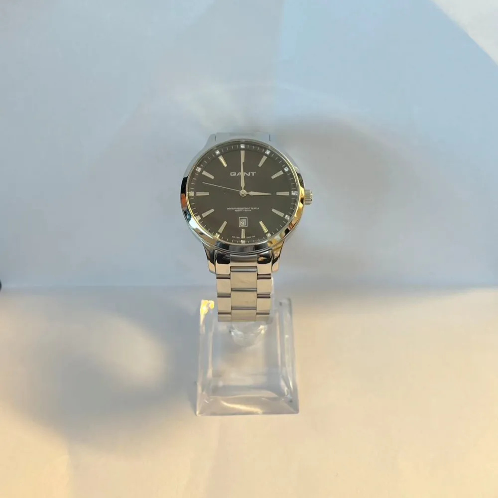 Snygg herrklocka från Gant med en stilren svart urtavla och datumvisning. Klockan har en silverfärgad boett och armband i rostfritt stål, vilket ger en tidlös look. Perfekt för den som vill ha en klassisk och elegant stil.. Asusteet.