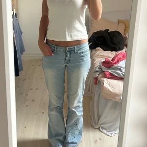 Ljusblå lågmidjade jeans  - Snygga ljusblå jeans med bootcut och broderi på enat benet. Innerbenslängden är 82. Finns en liten defekt på ens bakfickan-bild 5