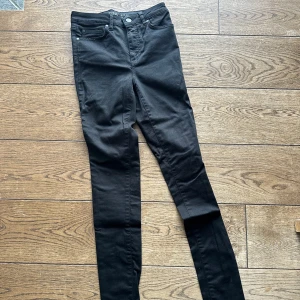 Svarta skinny jeans från Unique Denim - Snyggaste svarta skinny jeans från Unique Denim, modell High Waist Hannah. De är högmidjade och har en klassisk femficksdesign med knapp och dragkedja framtill.  Använda 2 gånger.