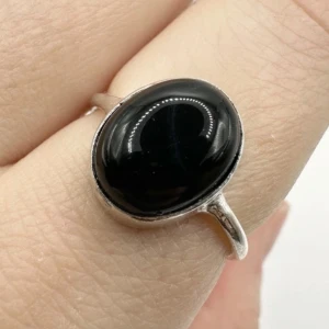 Elegant handgjord silverring med svart onyx – stilren och tidlös - Vacker handgjord ring med en svart onyx i cabochonslipning. Onyx sägs ha beskyddande egenskaper och ge bäraren styrka och självförtroende. 	•	Storlek: 18 (innerdiameter ca 18 mm) 	•	Material: Silverpläterad med 925 sterling silver, svart onyx 	•	Skick: Mycket fint  En stilren och prisvärd ring som passar både till vardag och fest. Perfekt för dig som älskar unika smycken!  Bundle 