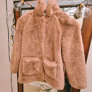 Beige teddyjacka från H&M - Mysig beige teddyjacka från H&M med knappar framtill. Jackan har en fluffig textur och två stora fickor fram. Perfekt för kyliga dagar när du vill känna dig som en vandrande kram.