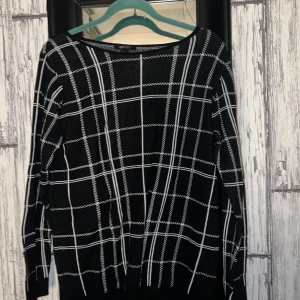 Svart och vit rutig tröja från Esmara - Snygg svart tröja med vitt rutmönster från Esmara. Perfekt för en stilren look. Tröjan har långa ärmar och en klassisk passform. Ett måste i garderoben för den som gillar tidlös design.