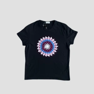 Svart t-shirt med Dreamcatcher mönster - Snygg svart t-shirt med ett färgglatt, cirkulärt mönster i mitten som liknar en dreamcatcher. Perfekt för att ge din outfit en unik touch. T-shirten har en normal passform och korta ärmar.