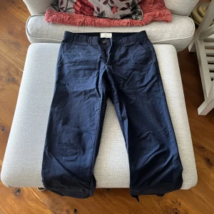 Mörkblå chinos från Cortefiel - Snygga mörkblå chinos från Cortefiel i slim fit. Byxorna har en klassisk design med knappar och dragkedja framtill. Perfekta för en stilren look.