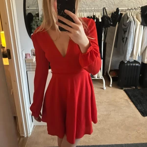 Röd klänning med v-ringning - Snygg röd klänning med v-ringning och långa ärmar. Den har en knytning i midjan och en dragkedja bak❣️❣️