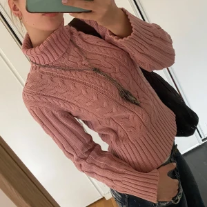 Rosa stickad polotröja - Säljer en mysig rosa stickad polotröja med kabelstickat mönster. Tröjan har långa ärmar och en hög polokrage som håller dig varm under kyliga dagar. Perfekt för höst och vinter!