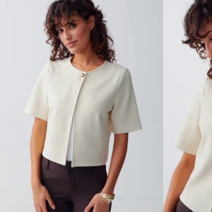 Vit kavaj med kortärmad design - Elegant vit kavaj med kortärmad design och en enkel knapp framtill. Passar bra till både byxor och kjol.