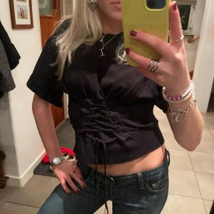 Svart kortärmad topp med snörning - Så fin och cool svart kortärmad topp med snygg snörning framtill. Från Stay i storlek S