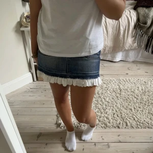 Jeanskjol med spetsdetalj - Trendig jeanskjol i blått med söt spetskant längst ner. Perfekt för en avslappnad stil. Kjolen har en kort längd och en normal passform.