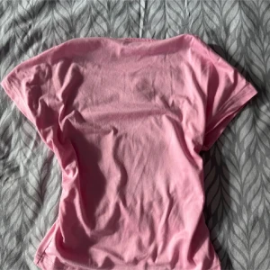 Rosa öppen rygg t-shirt - Säljer en enkel och stilren rosa t-shirt med  öppen rygg. Perfekt för en avslappnad look. Passar bra till jeans eller shorts.