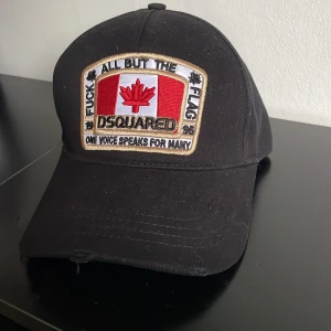 Svart keps från Dsquared2 - Snygg svart keps från Dsquared2 med broderad patch framtill och texten 'Born in Canada' baktill. Kepsen har justerbart spänne och är tillverkad i bomull. 