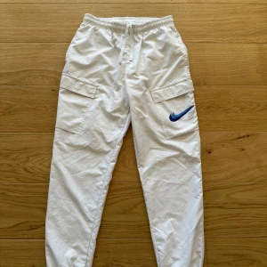 Nike byxor  - Väldigt sköna och bekväma byxor från märket nike, vita träningsbyxor med blått nike märke på vänster ben.   Mått: Längd 98 cm och midja/bredd 36 cm Storlek: M Skick: Väldigt bra ser ut som nya Frakt: skickas samma dag innan 20:00 Hör av er vid minsta fundering så svara jag på det inom 10 minuter.