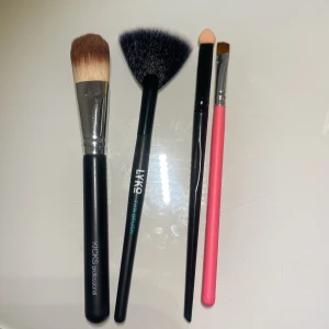 Fyra sminkborstar från KICKS och LYKO - Säljer fyra olika sminkborstar: en platt foundationborste från KICKS, en svart solfjäderborste från LYKO, en svart ögonskuggsborste med svampapplikator och en rosa borste med snedskuren topp. Perfekt för bas, highlighter och ögonskuggor.