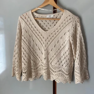 Beige stickad tröja från JDY - Säljer en beige stickad tröja från JDY med v-ringning och trekvartsärm. Tröjan har ett fint hålmönster och vågig kant nertill, perfekt för lager-på-lager. Superfin till både jeans och kjol! Använd vid 3 tillfällen