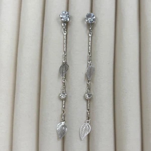 Långa silverfärgade örhängen med löv och stenar - Säljer ett par eleganta, långa örhängen i silverfärg med gnistrande stenar och små dekorativa lövdetaljer. Perfekta för att ge en stilren touch till din look. Passar dig som gillar smycken med naturinspirerade detaljer.