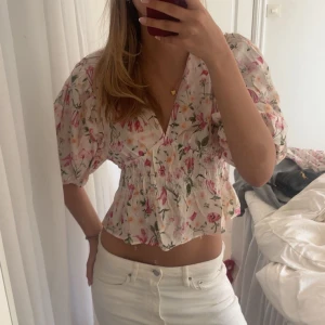 Jättesöt blommig blus - Säljer en såå söt blommig blus med korta puffärmar och smockad midja. ❣️❣️Blusen har v-ringning och volang nertill, perfekt för vår och sommar. Helst slutsåld på hemsidan. Storlek s med lapp kvar, aldrig använd