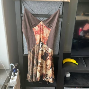 Patchwork klänning från Jaded London - Unik patchwork klänning från Jaded London med blandade mönster i bruna, beige och orange toner. Klänningen har smala axelband, ärmlös design och flera olika tygpaneler med både blommigt och rutigt mönster. Jag använder den som en topp då den är liten i storleken