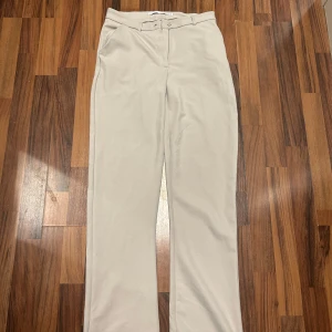Beiga kostymbyxor med raka ben - Snygga beiga kostymbyxor med normal passform och raka ben. Byxorna har hög midja, diskreta sidfickor och stängs med knapp och dragkedja. Perfekta för en stilren look. Från Lager157. Storlek XS men stora i storlek. Helt nya & aldrig använda. Säljes då de är för stora för mig.