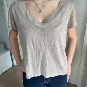 Beige v-ringad topp, lite off shoulder - Säljer en beige topp med djup v-ringning från Zara💞. Tunt och mjukt material, korta ärmar och avslappnad passform. Man kan även bära den som en off-shoulder topp