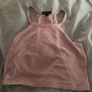 Rosa ribbad croppad linnetopp - Säljer en ljusrosa ribbad croppad linnetopp med brottarrygg. Perfekt för varma dagar och enkel att matcha med jeans eller kjol. Mjuk och stretchig för en bekväm passform.