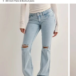 Bootcut jeans i ljusblå denim med slitningar - Bootcut jeans i ljusblå denim med slitna knän och broderade detaljer på bakfickorna. Klassisk femficksmodell med normal passform och låg midja. Perfekta för en avslappnad och trendig look. Nyskick använda en gång. Dom är uppsydda så dom passar dig som är 164 eller kortare, skriv om ni vill ha bilder❣️