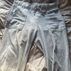Juicy Couture byxor  - Säljer ett par grå Juicy Coutoure byxor med knappfickor där bak