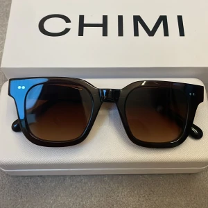 Bruna solglasögon från CHIMI  - Stilrena solglasögon 04 CHIMI med fyrkantig form och mörktonade glas. Snygg och modern design som passar perfekt till sommaren.☀️⛱️