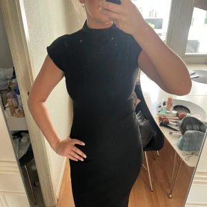 Svart tight midiklänning med hög hals - Säljer en svart tight klänning med hög hals och korta ärmar. 