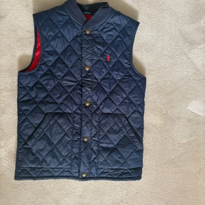 Mörkblå quiltad väst från Ralph Lauren - Säljer en snygg mörkblå quiltad väst från Ralph Lauren. Knappt använd och mycket bra skick! Nypris ca 2200