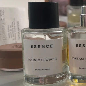 ESSNCE Iconic Flower Eau de Parfum - Fräsch och blommig parfym från ESSNCE med namnet Iconic Flower. Flaskan är genomskinlig med en enkel vit etikett och svart lock. Modern och stilren design som passar perfekt på parfymhyllan.